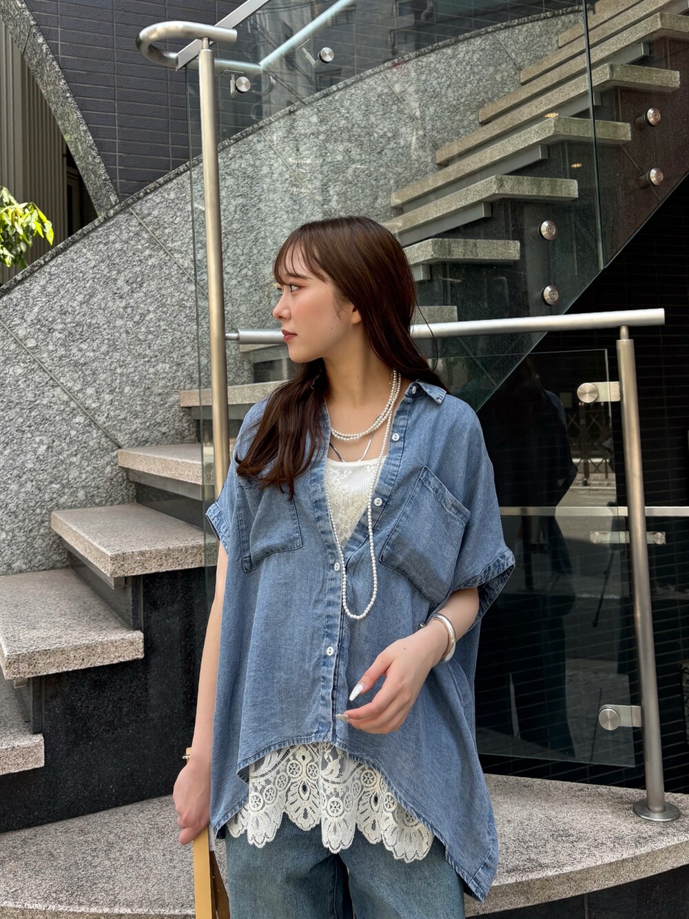 ブルー系のデニムパンツ、ホワイト系のシャツ/ブラウス、イエロー系のショルダーバッグを着用したレディースの春コーディネートの2枚目の写真