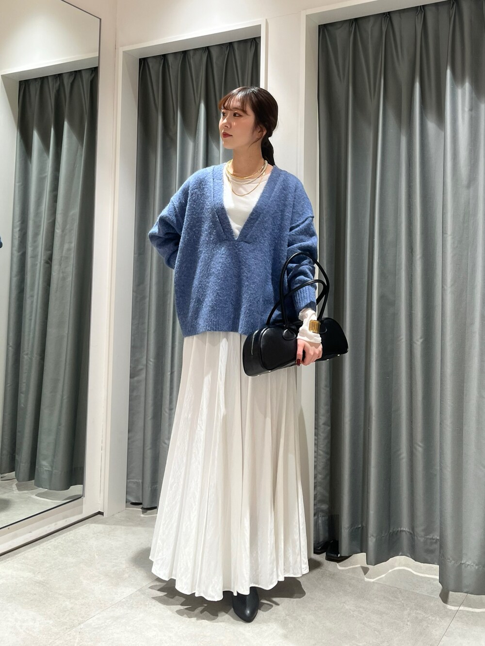 ホワイト系のスカート、ブラック系のショルダーバッグ、ブルー系のニット/セーターを着用したレディースの冬コーディネートの3枚目の写真