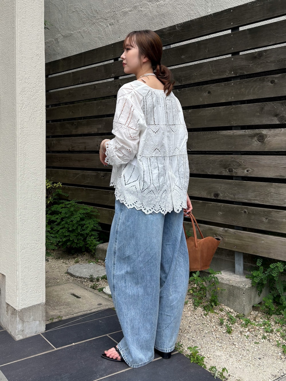 ブルー系のデニムパンツ、ブラック系のサンダル、ホワイト系のシャツ/ブラウスを着用したレディースの夏コーディネートの2枚目の写真