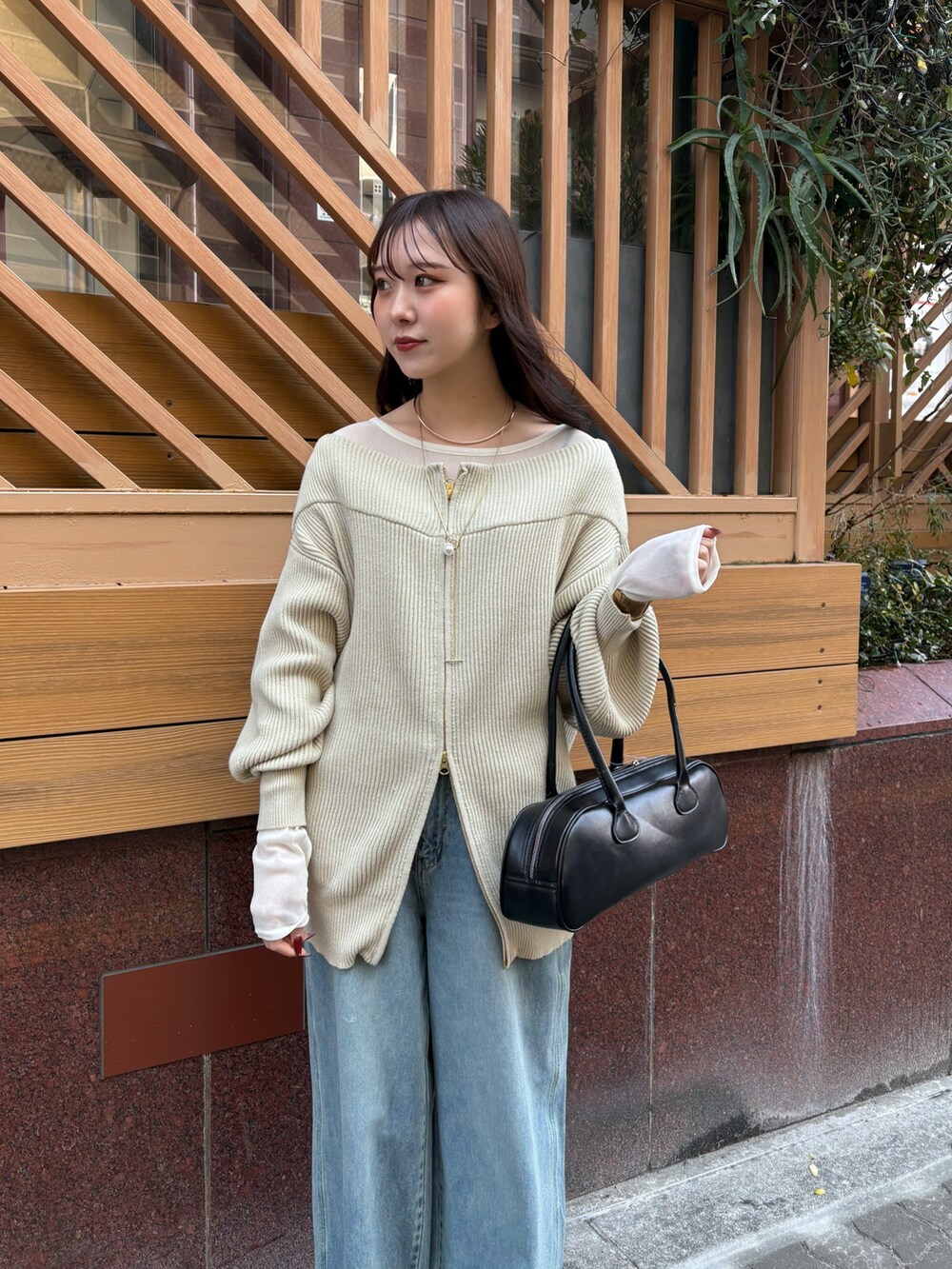 ブルー系のデニムパンツ、ブラック系のショルダーバッグ、ベージュ系のニット/セーターを着用したレディースの冬コーディネートの2枚目の写真