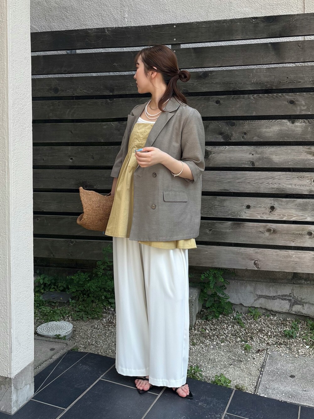 ホワイト系のスラックス、ブラック系のサンダル、ベージュ系のシャツ/ブラウスを着用したレディースの夏コーディネートの2枚目の写真