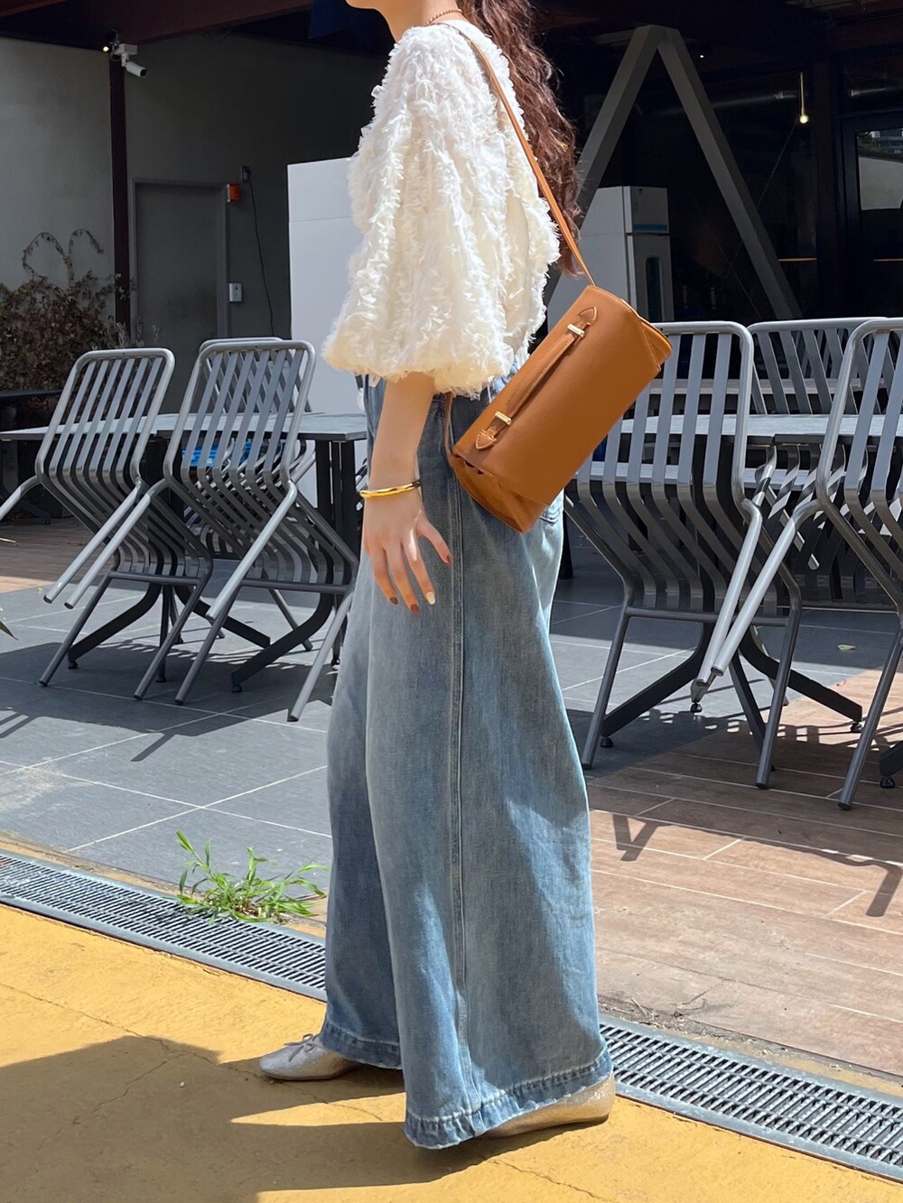 ブルー系のデニムパンツ、ピンク系のバレエシューズ、ブラウン系のショルダーバッグを着用したレディースの秋コーディネートの3枚目の写真