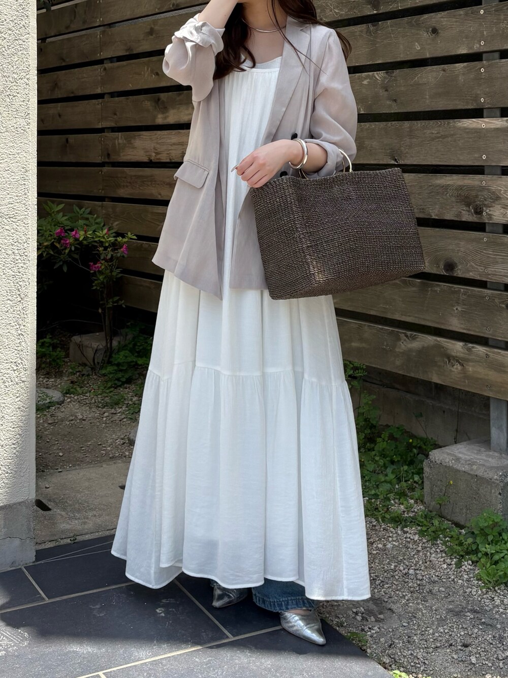 ブルー系のデニムパンツ、グレー系のワンピース、ベージュ系のテーラードジャケットを着用したレディースの春コーディネートの5枚目の写真