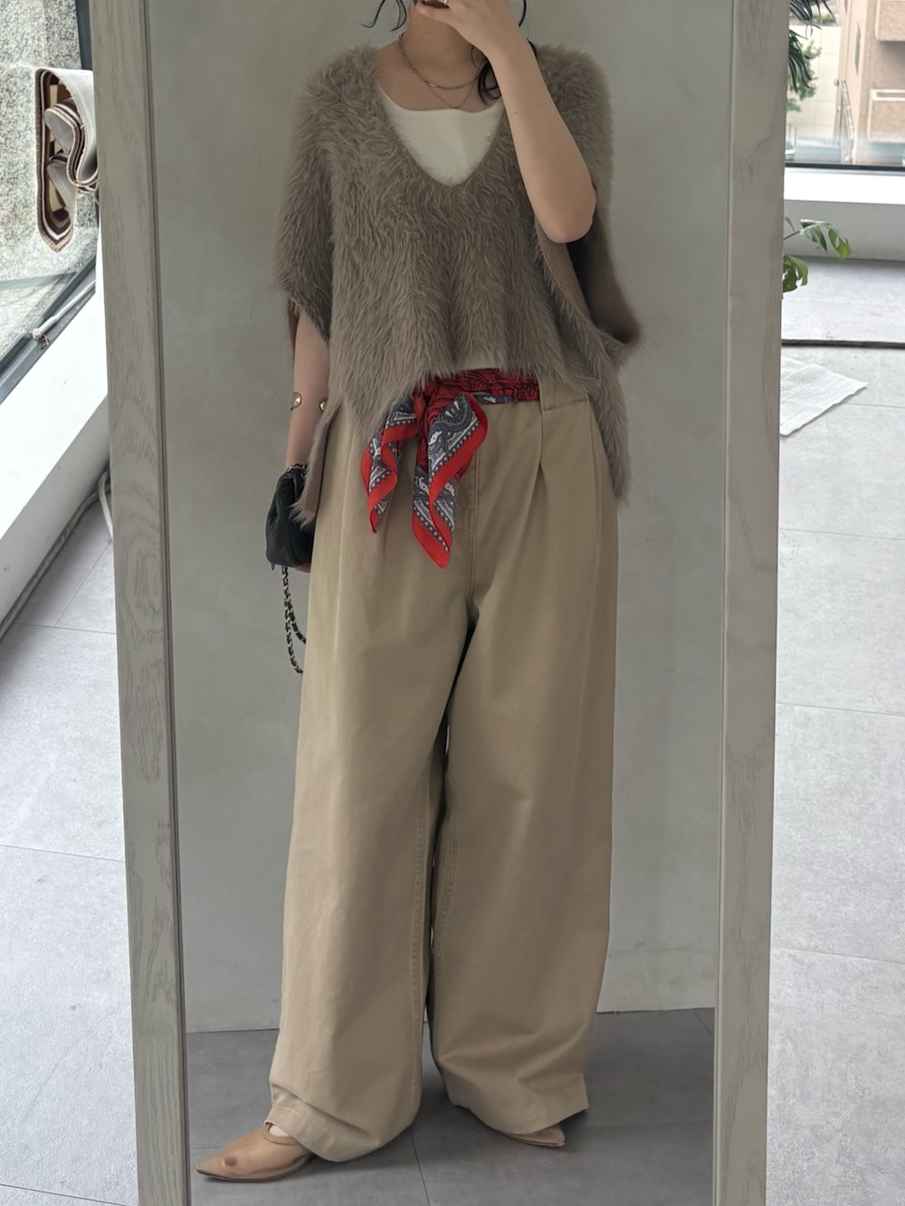 ベージュ系のチノパンツ、ベージュ系のニット/セーター、ホワイト系のタンクトップを着用したレディースの秋コーディネートの2枚目の写真