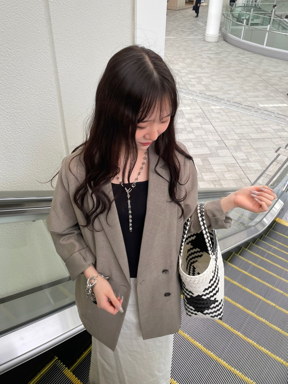 ホワイト系のバッグ、ホワイト系のスカート、ベージュ系のテーラードジャケットを着用したレディースの夏コーディネートの3枚目の写真