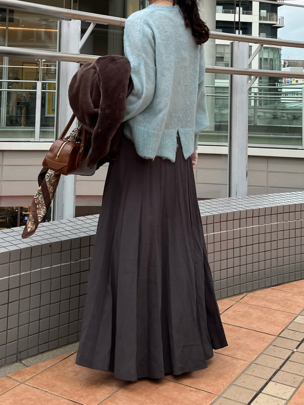 グレー系のスカート、ブラウン系のショルダーバッグ、ブラウン系のその他アウターを着用したレディースの冬コーディネートの5枚目の写真