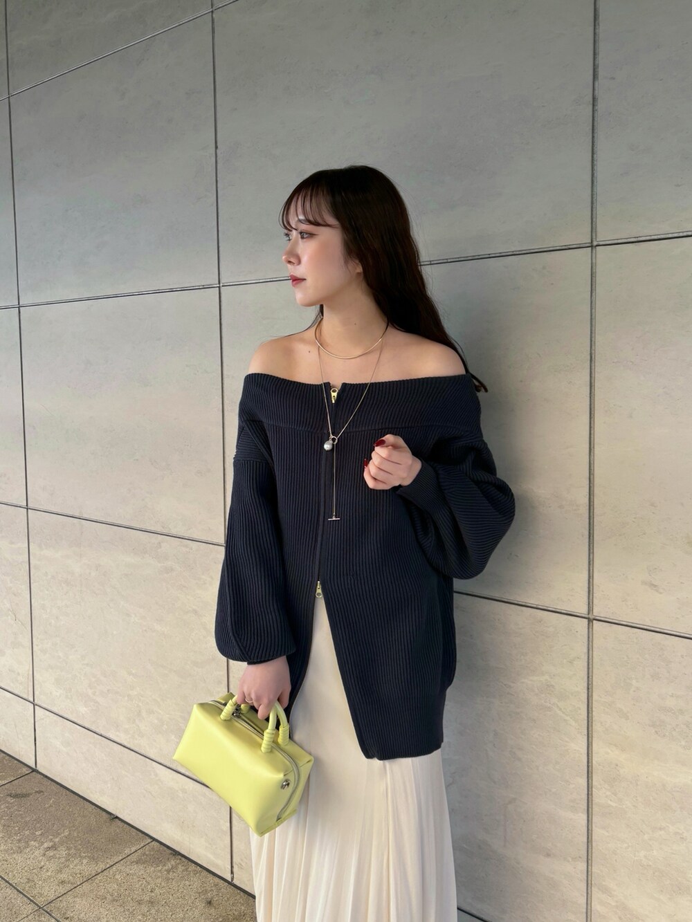 ブルー系のニット/セーター、ホワイト系のスカート、イエロー系のショルダーバッグを着用したレディースの冬コーディネートの2枚目の写真