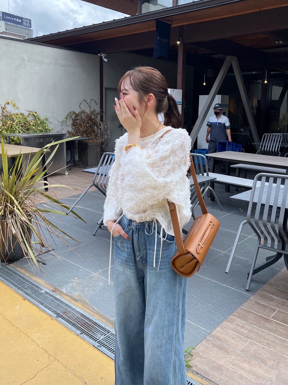 ブルー系のデニムパンツ、ピンク系のバレエシューズ、ブラウン系のショルダーバッグを着用したレディースの秋コーディネートの4枚目の写真