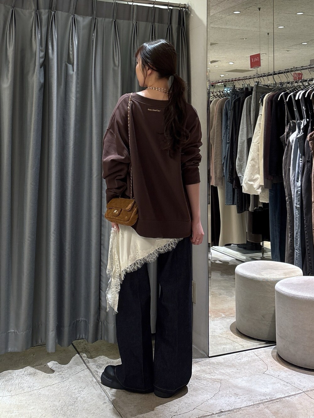 ブラウン系のスウェット、ホワイト系のキャミソール、ブルー系のデニムパンツを着用したレディースの冬コーディネートの2枚目の写真