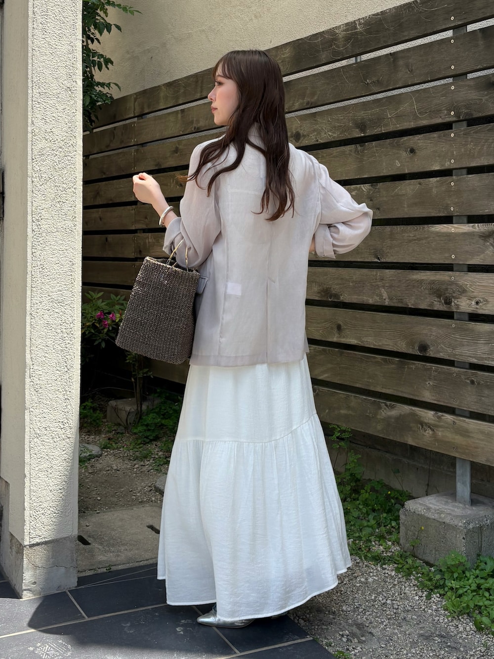 ブルー系のデニムパンツ、グレー系のワンピース、ベージュ系のテーラードジャケットを着用したレディースの春コーディネートの2枚目の写真
