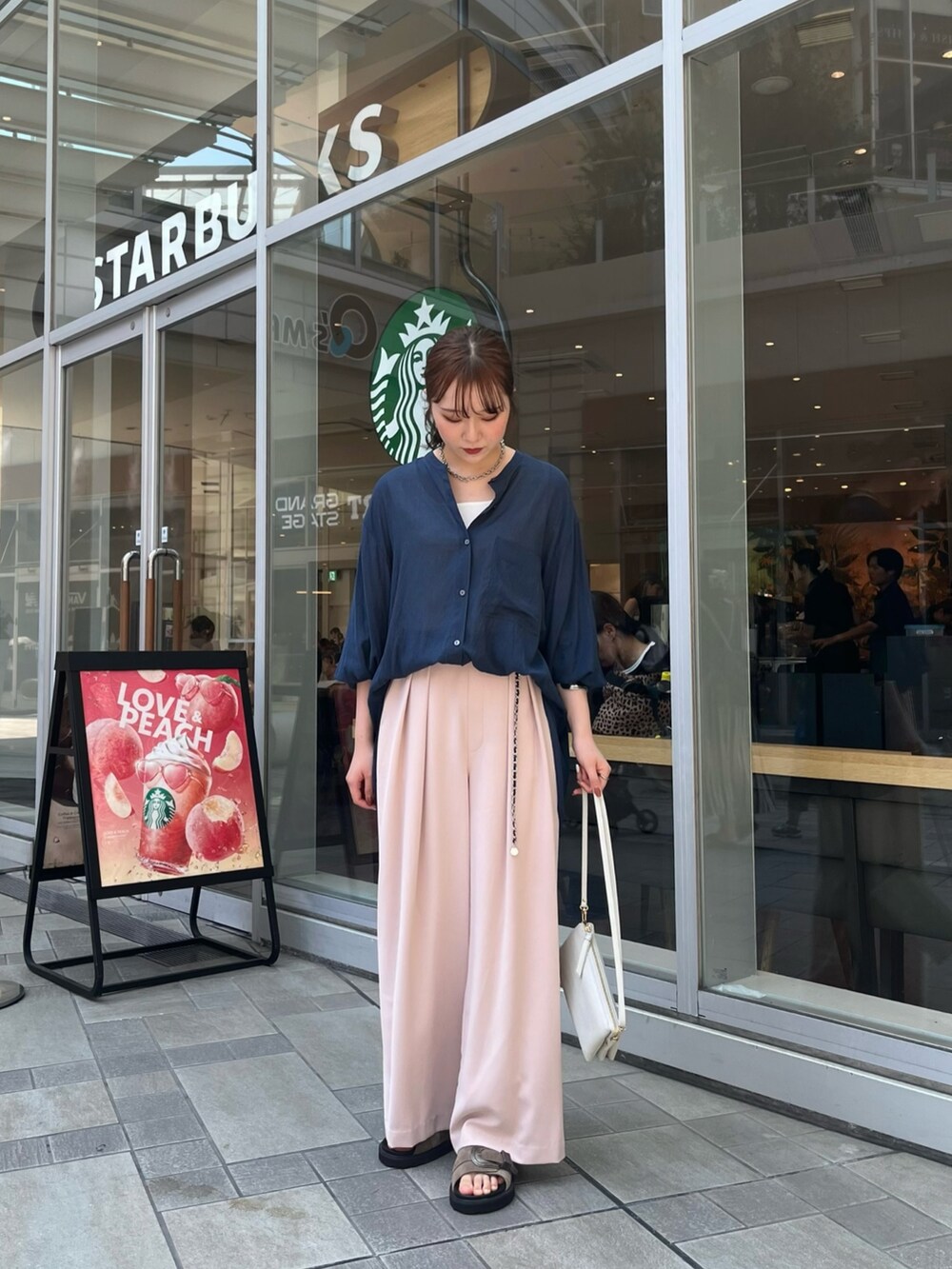 ピンク系のスラックス、ブルー系のシャツ/ブラウス、ホワイト系のタンクトップを着用したレディースの夏コーディネートの2枚目の写真