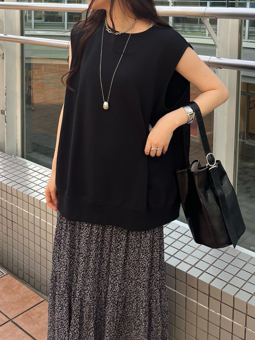 ブラック系のスウェット、ピンク系のスカート、ブラック系のバッグを着用したレディースの夏コーディネートの7枚目の写真