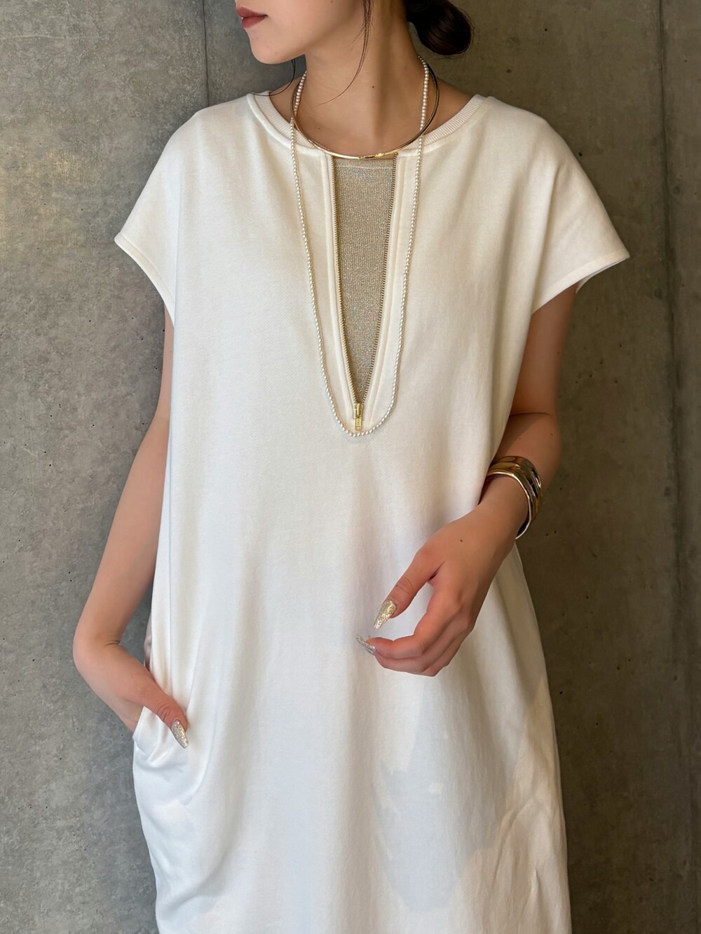 ホワイト系のワンピース、ブルー系のデニムパンツ、ベージュ系のニット/セーターを着用したレディースの春コーディネートの4枚目の写真