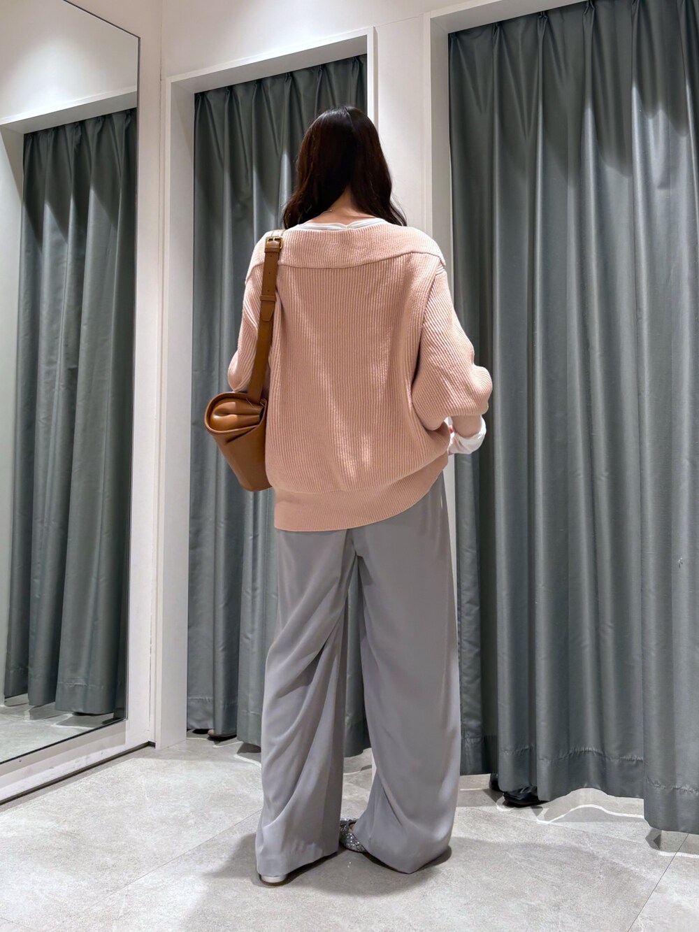 ベージュ系のスラックス、ピンク系のニット/セーター、ブラウン系のショルダーバッグを着用したレディースの冬コーディネートの2枚目の写真