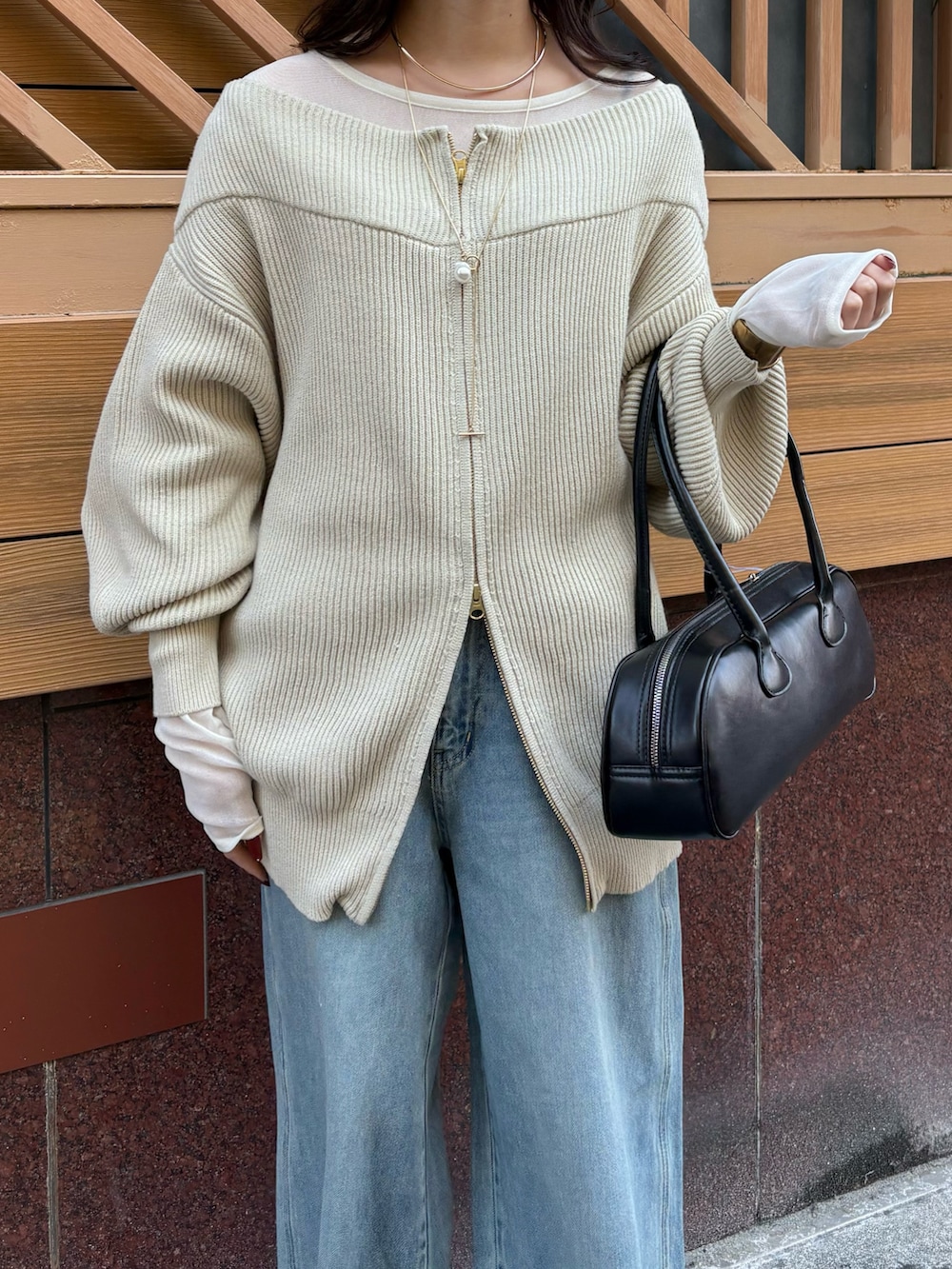 ブルー系のデニムパンツ、ブラック系のショルダーバッグ、ベージュ系のニット/セーターを着用したレディースの冬コーディネートの7枚目の写真