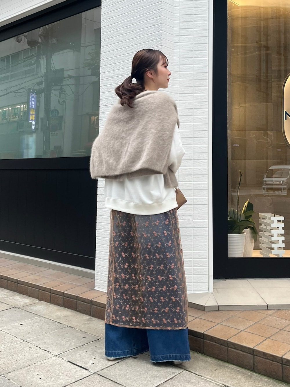 ピンク系のスカート、ブルー系のデニムパンツ、ベージュ系のショルダーバッグを着用したレディースの秋コーディネートの5枚目の写真