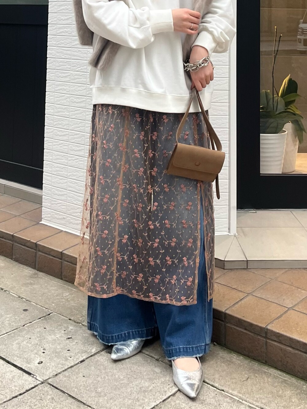 ピンク系のスカート、ブルー系のデニムパンツ、ベージュ系のショルダーバッグを着用したレディースの秋コーディネートの7枚目の写真