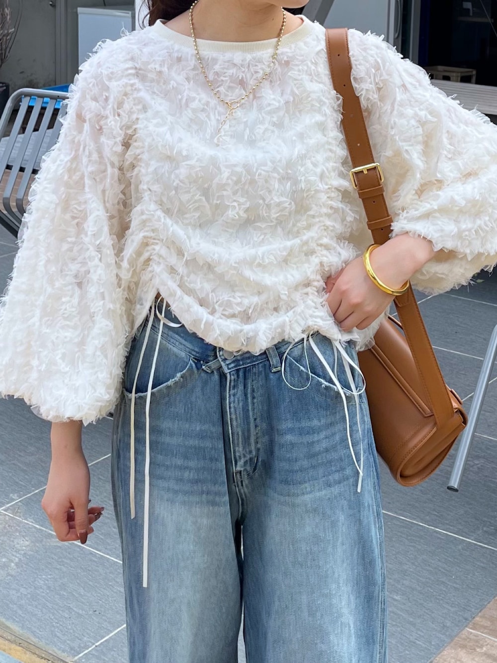 ブルー系のデニムパンツ、ピンク系のバレエシューズ、ブラウン系のショルダーバッグを着用したレディースの秋コーディネートの6枚目の写真