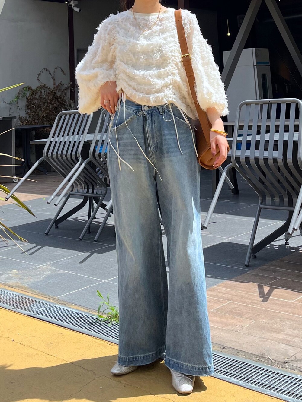 ブルー系のデニムパンツ、ピンク系のバレエシューズ、ブラウン系のショルダーバッグを着用したレディースの秋コーディネートの2枚目の写真