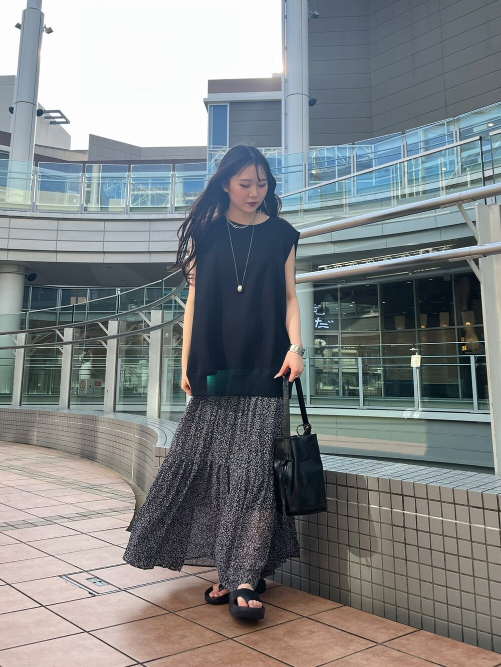 ブラック系のスウェット、ピンク系のスカート、ブラック系のバッグを着用したレディースの夏コーディネートの2枚目の写真