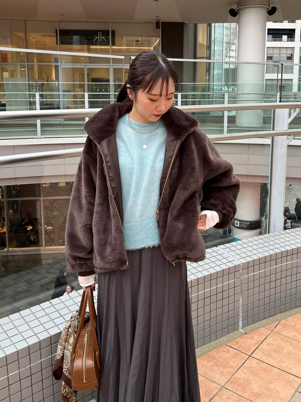 グレー系のスカート、ブラウン系のショルダーバッグ、ブラウン系のその他アウターを着用したレディースの冬コーディネートの7枚目の写真