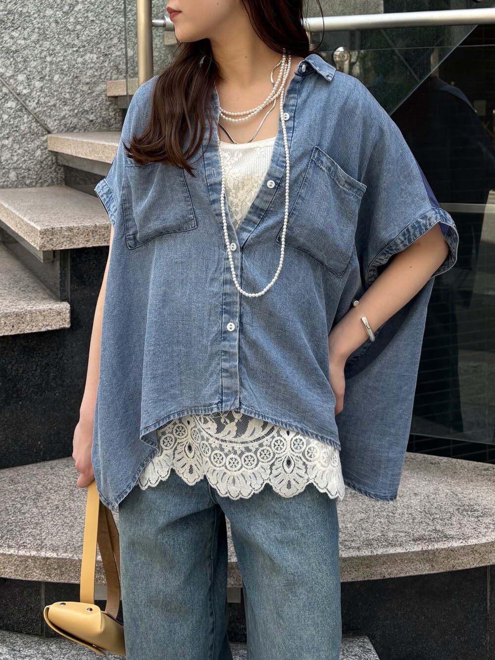 ブルー系のデニムパンツ、ホワイト系のシャツ/ブラウス、イエロー系のショルダーバッグを着用したレディースの春コーディネートの4枚目の写真