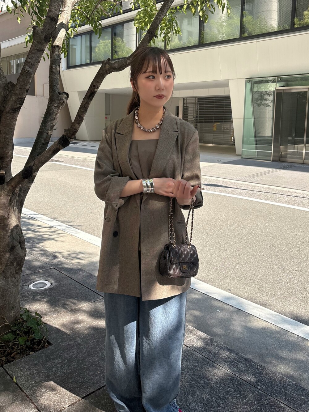 ブラウン系のテーラードジャケット、グリーン系のシャツ/ブラウス、ブルー系のデニムパンツを着用したレディースの夏コーディネートの3枚目の写真