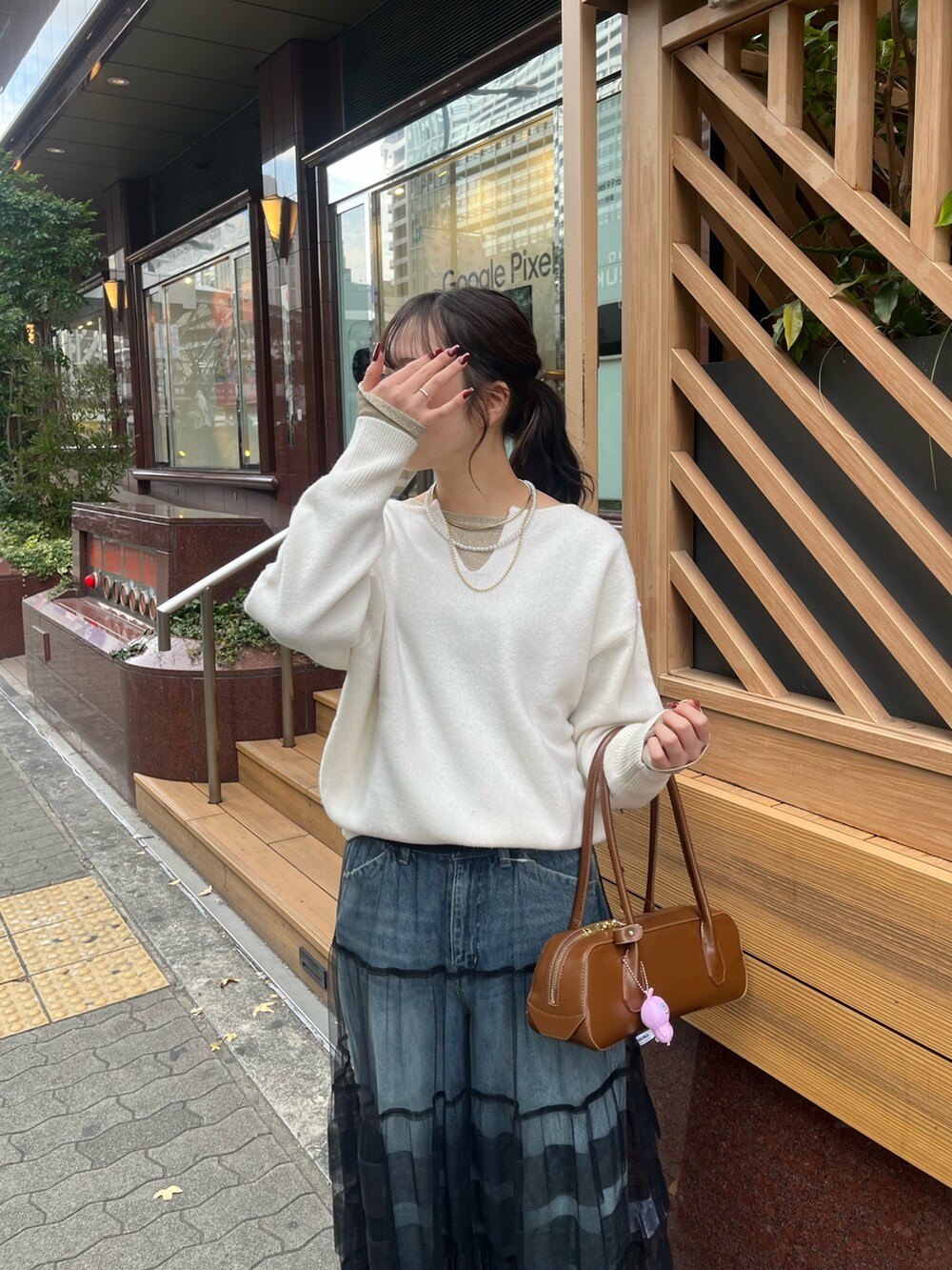 ブルー系のデニムパンツ、ブラック系のスカート、ホワイト系のニット/セーターを着用したレディースの冬コーディネートの6枚目の写真