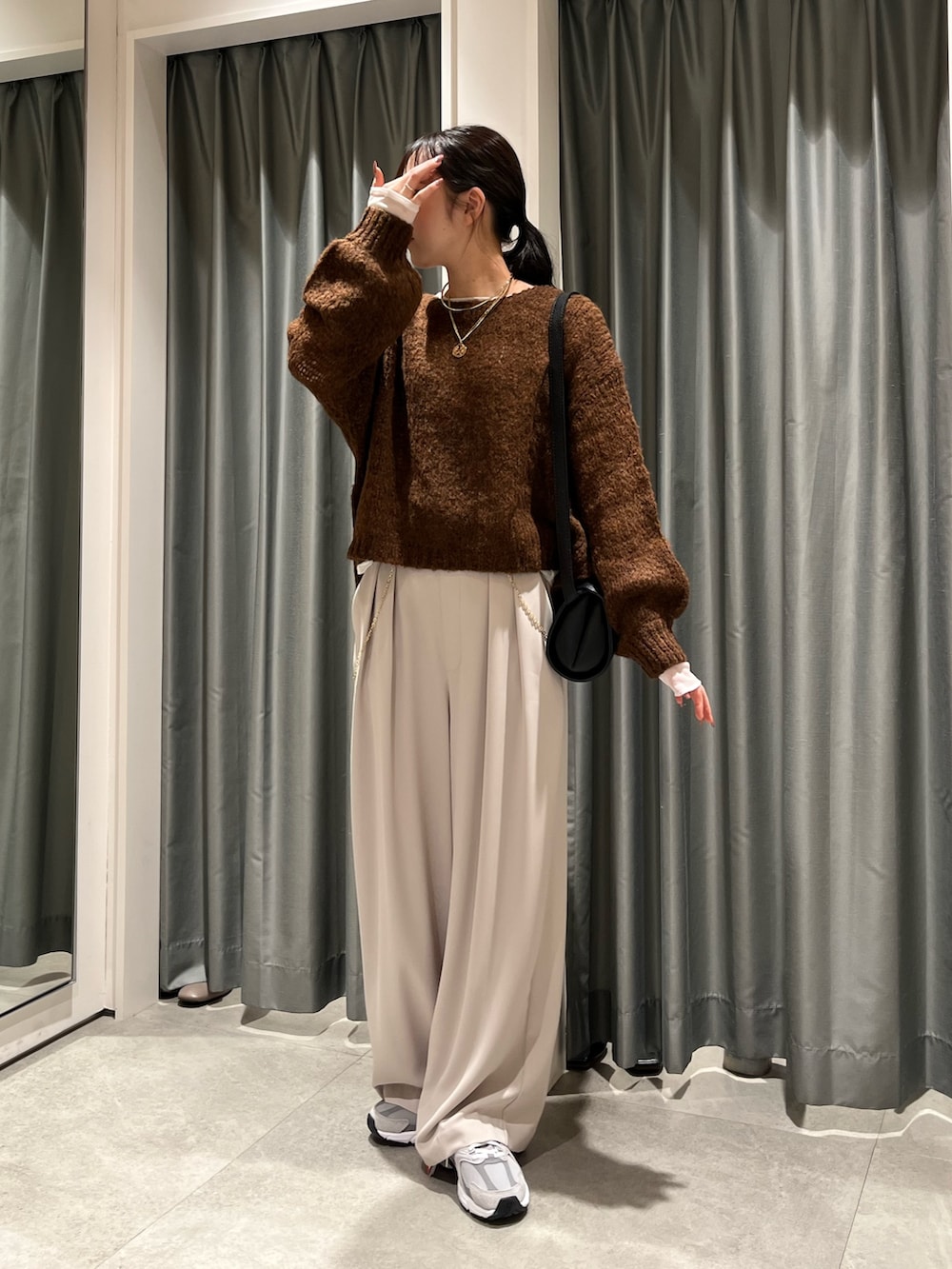 グレー系のスラックス、ホワイト系のTシャツ/カットソー、ブラウン系のニット/セーターを着用したレディースの冬コーディネートの2枚目の写真