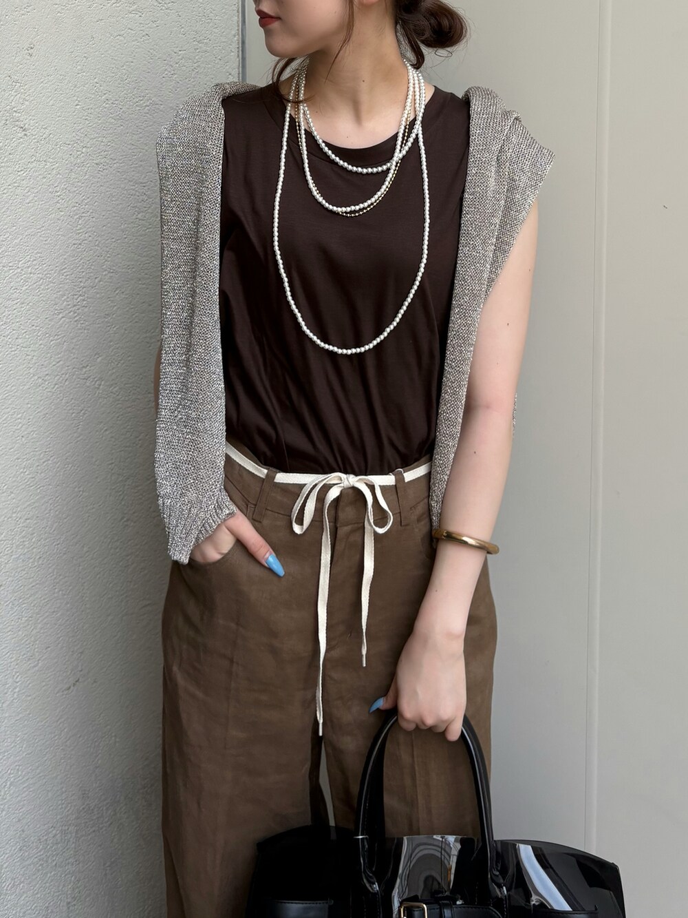 ブラック系のサンダル、ブラック系のショルダーバッグ、ゴールド系のニット/セーターを着用したレディースの夏コーディネートの5枚目の写真