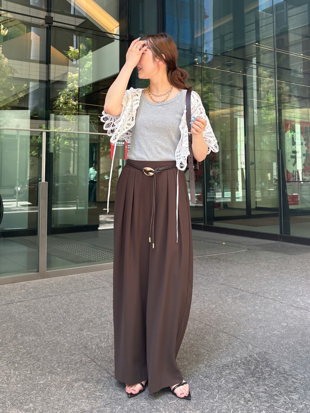 ブラウン系のスラックス、ブラック系のサンダル、グレー系のTシャツ/カットソーを着用したレディースの夏コーディネートの3枚目の写真
