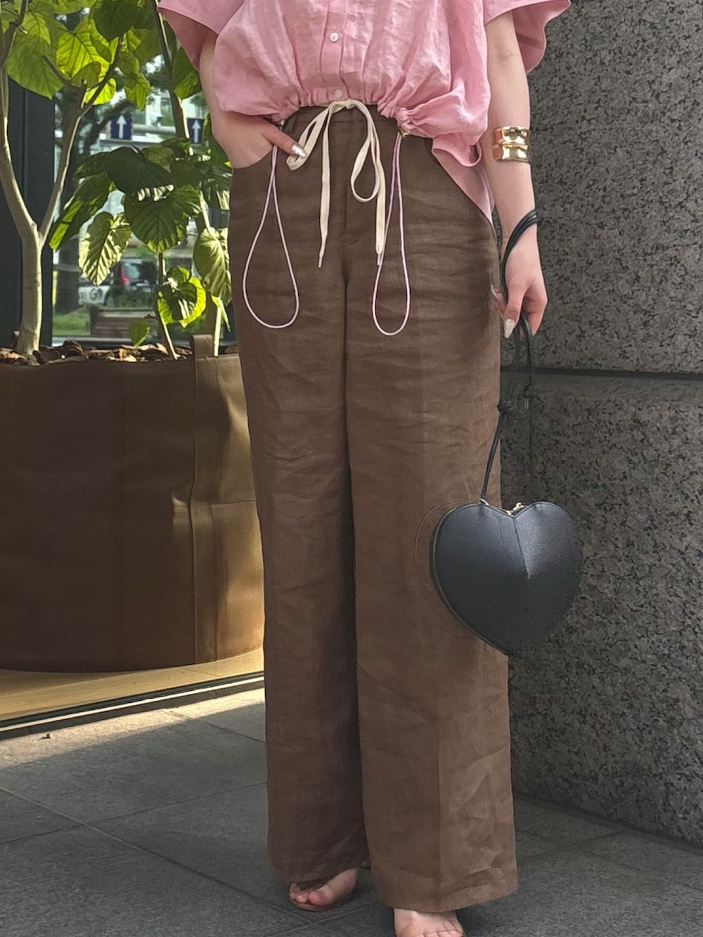 ピンク系のシャツ/ブラウス、ブラウン系のその他パンツ、ブラック系のショルダーバッグを着用したレディースの夏コーディネートの3枚目の写真