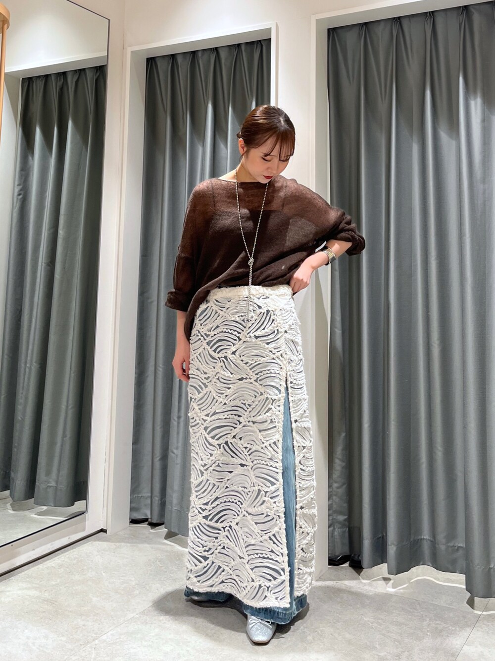 ブルー系のデニムパンツ、シルバー系のバレエシューズ、ホワイト系のスカートを着用したレディースの夏コーディネートの5枚目の写真