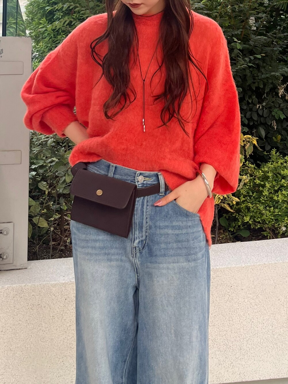 ブルー系のデニムパンツ、ブラウン系のショルダーバッグ、オレンジ系のニット/セーターを着用したレディースの秋コーディネートの5枚目の写真