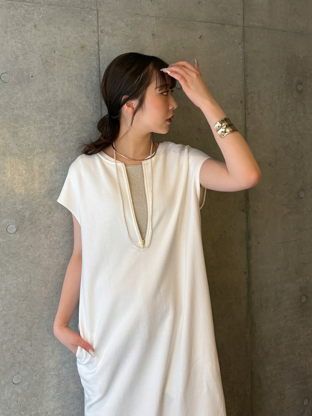 ホワイト系のワンピース、ブルー系のデニムパンツ、ベージュ系のニット/セーターを着用したレディースの春コーディネートの3枚目の写真