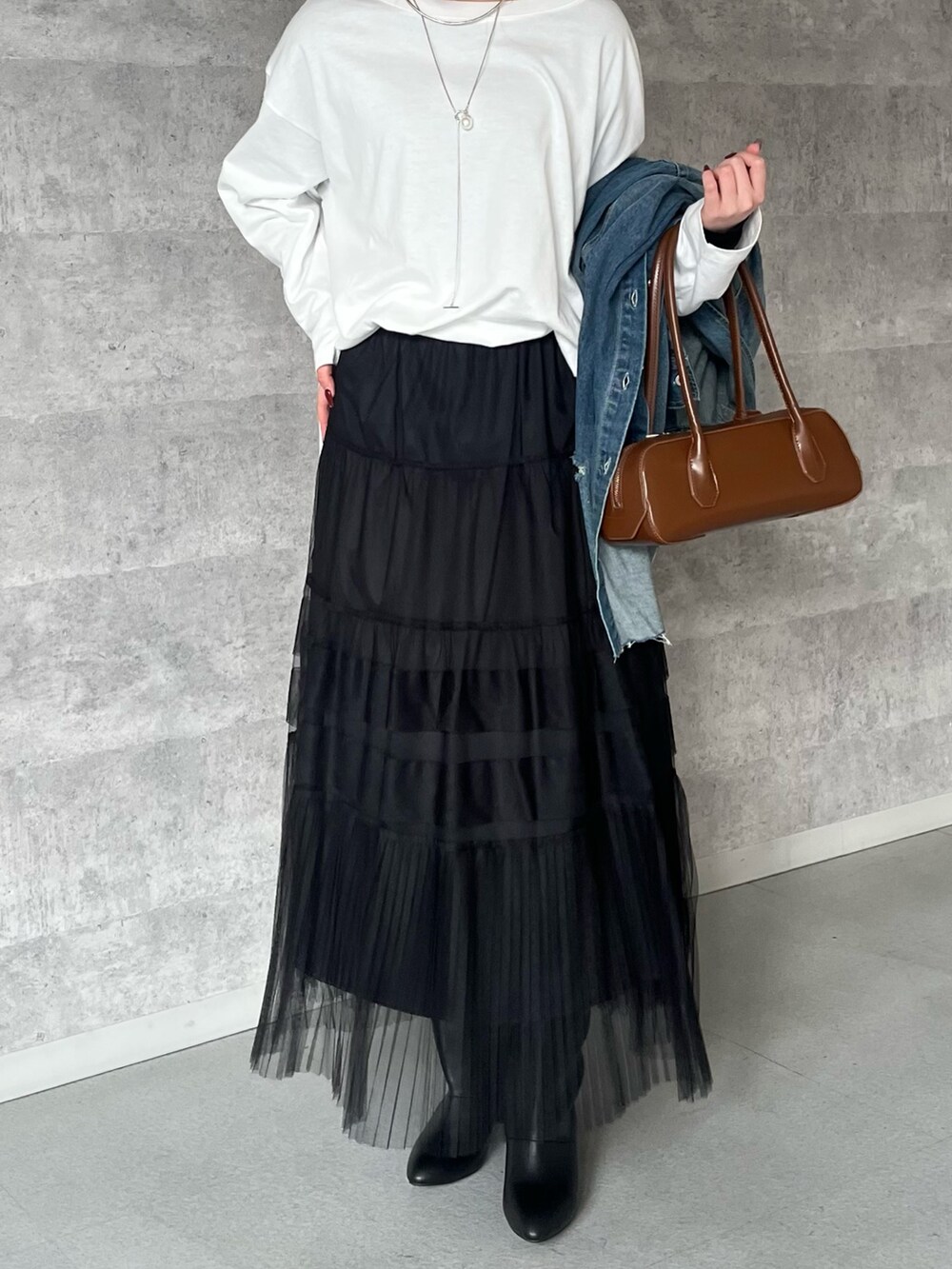 ブラック系のスカート、ブラウン系のショルダーバッグ、ホワイト系のTシャツ/カットソーを着用したレディースの冬コーディネートの5枚目の写真