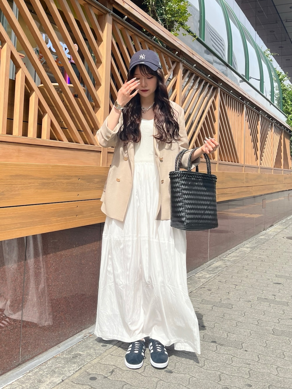 ベージュ系のテーラードジャケット、ホワイト系のワンピース、ブラック系のかごバッグを着用したレディースの夏コーディネートの2枚目の写真