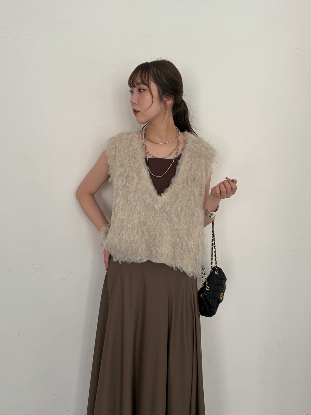 ブラウン系のタンクトップ、ブラック系のショルダーバッグ、ベージュ系のニット/セーターを着用したレディースの夏コーディネートの3枚目の写真