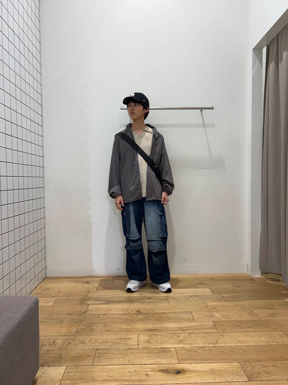 ブルー系のデニムパンツ、ブラック系のショルダーバッグ、グレー系のナイロンジャケットを着用したメンズの春コーディネートの2枚目の写真