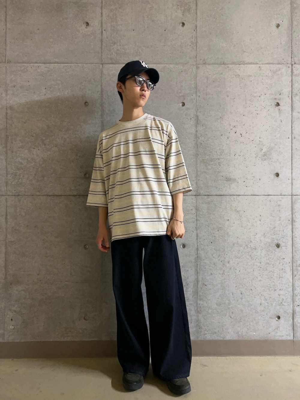 グレー系のTシャツ/カットソー、ブルー系のデニムパンツ、ブラック系のサングラスを着用したメンズの夏コーディネートの2枚目の写真