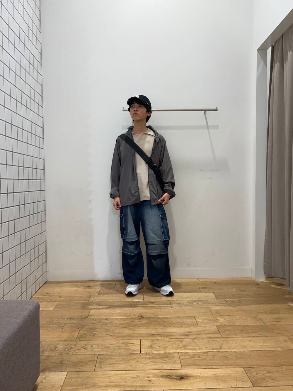 ブルー系のデニムパンツ、ブラック系のショルダーバッグ、グレー系のナイロンジャケットを着用したメンズの春コーディネートの3枚目の写真