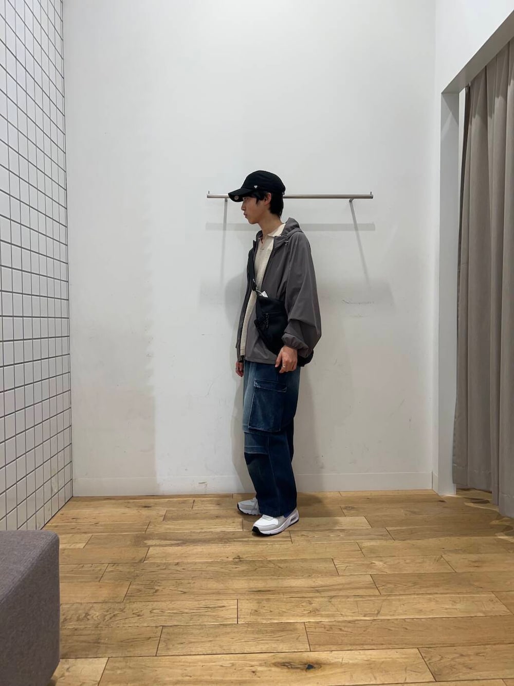 ブルー系のデニムパンツ、ブラック系のショルダーバッグ、グレー系のナイロンジャケットを着用したメンズの春コーディネートの4枚目の写真