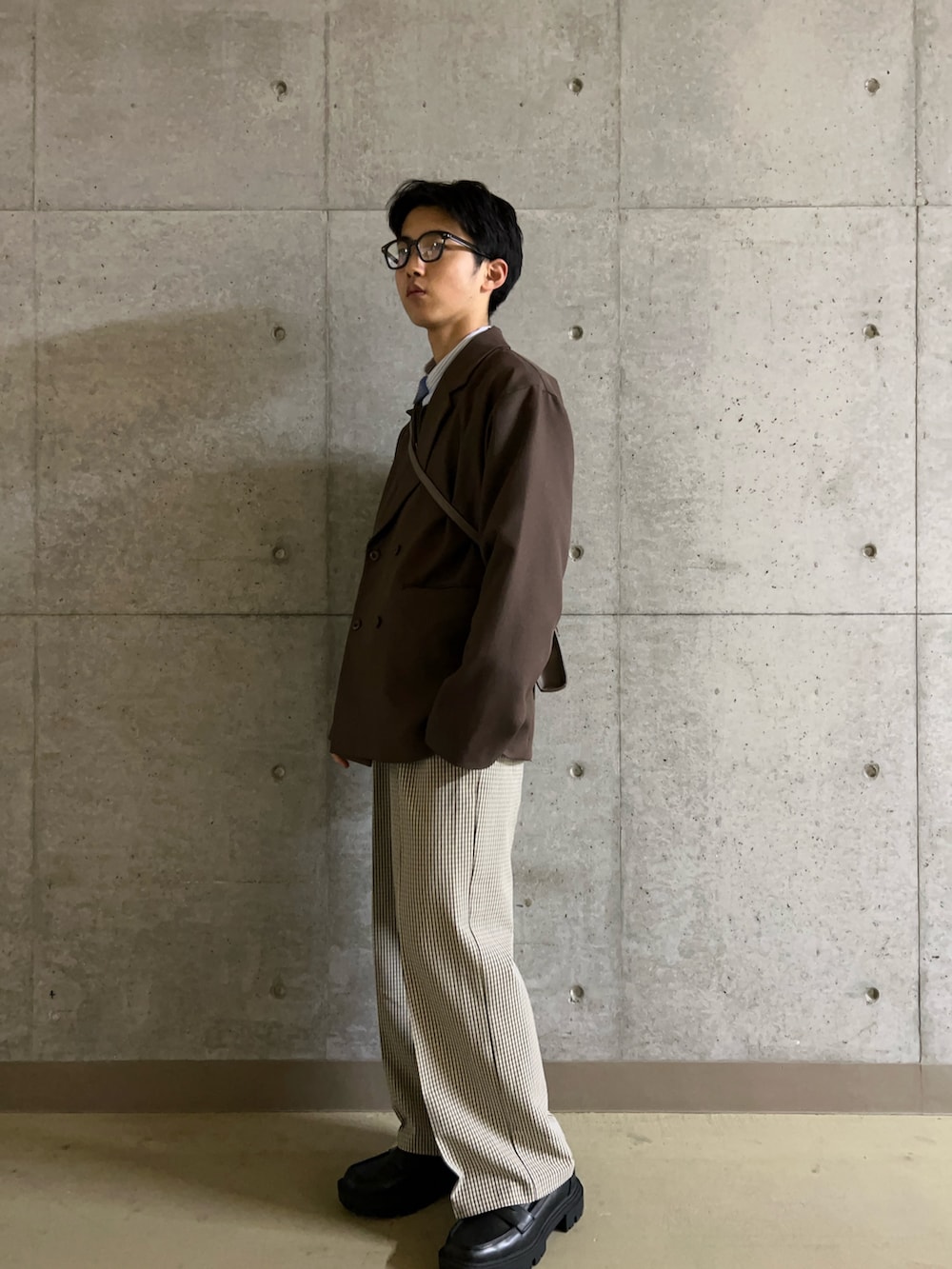 ブラック系のローファー、ベージュ系のスラックス、ブラウン系のショルダーバッグを着用したメンズの冬コーディネートの4枚目の写真