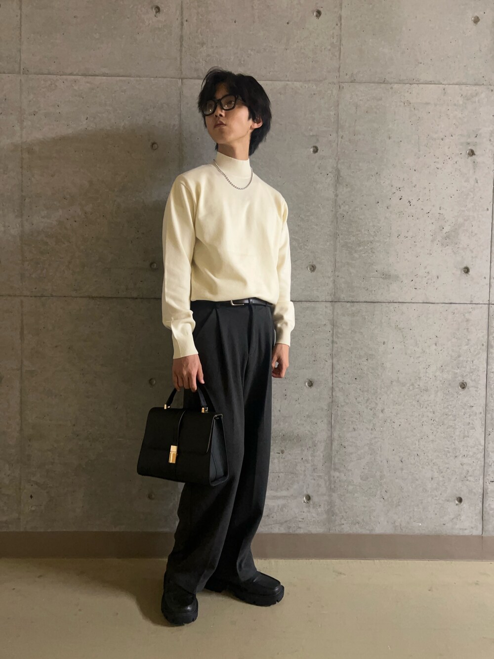 ブラック系のハンドバッグ、ホワイト系のニット/セーター、グレー系のその他パンツを着用したメンズの秋コーディネートの2枚目の写真