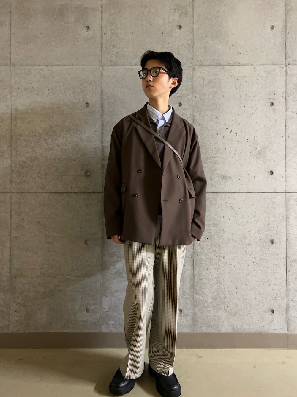 ブラック系のローファー、ベージュ系のスラックス、ブラウン系のショルダーバッグを着用したメンズの冬コーディネートの2枚目の写真