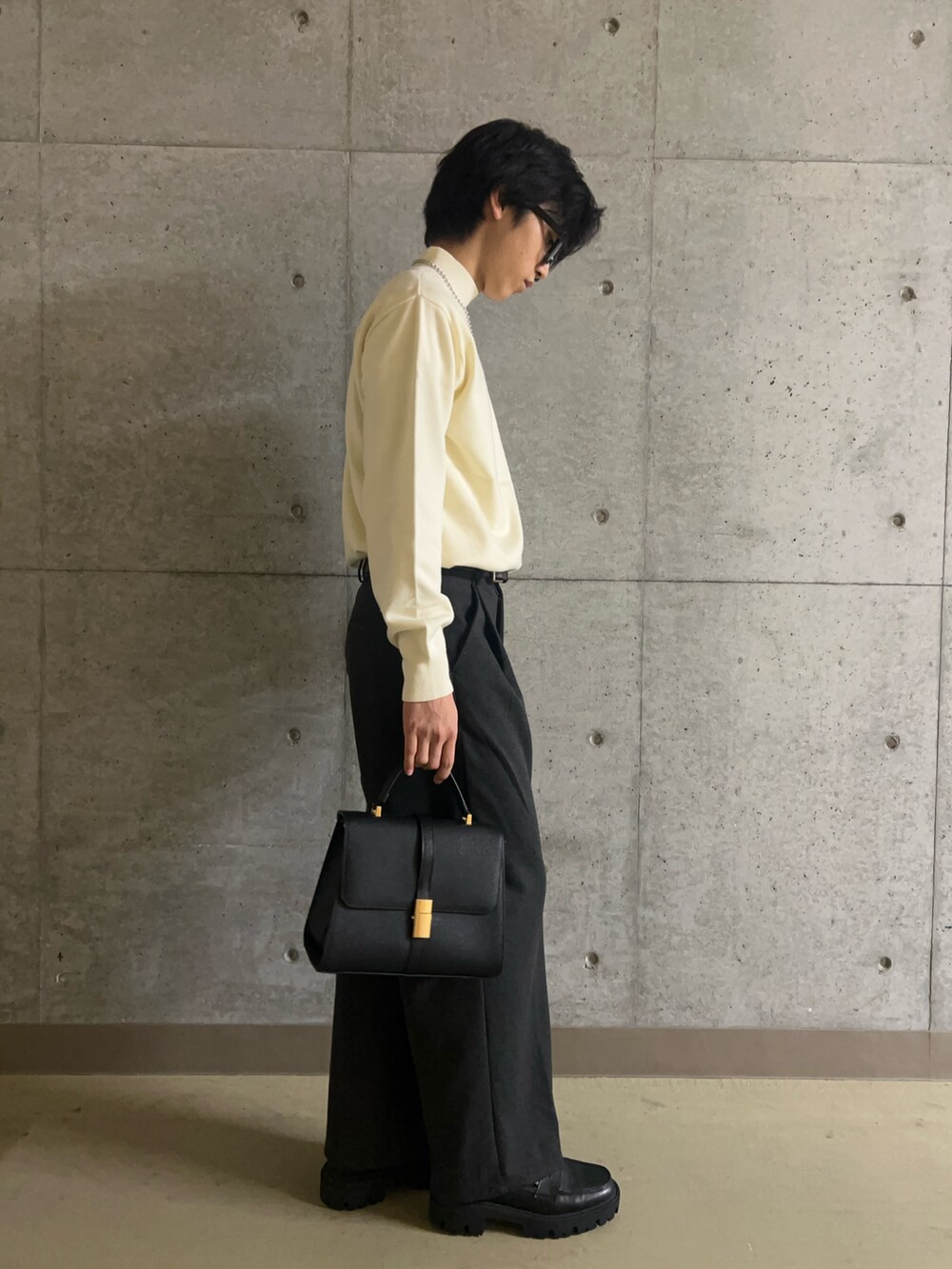 ブラック系のハンドバッグ、ホワイト系のニット/セーター、グレー系のその他パンツを着用したメンズの秋コーディネートの3枚目の写真