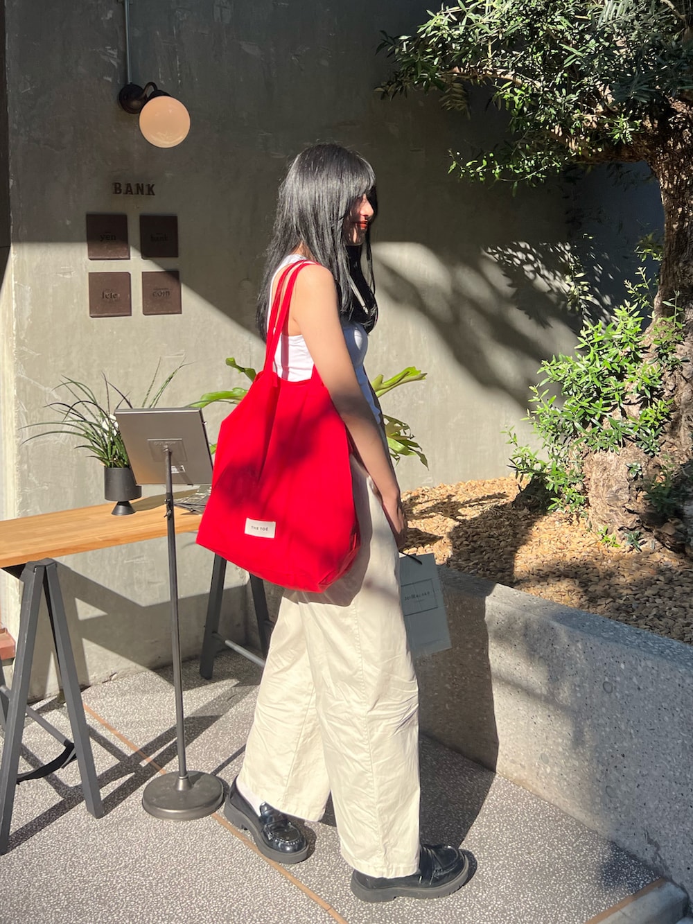 ブラック系のローファー、ホワイト系のタンクトップ、レッド系のバッグを着用したレディースの夏コーディネートの2枚目の写真