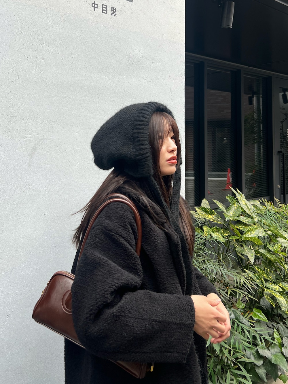 ブラック系のピーコート、ブラウン系のショルダーバッグ、ブラック系のデニムパンツを着用したレディースの冬コーディネートの2枚目の写真