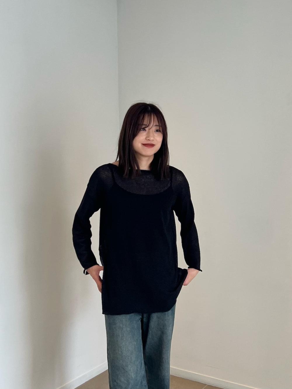 ブラック系のニット/セーター、ブルー系のデニムパンツを着用したレディースの夏コーディネートの3枚目の写真