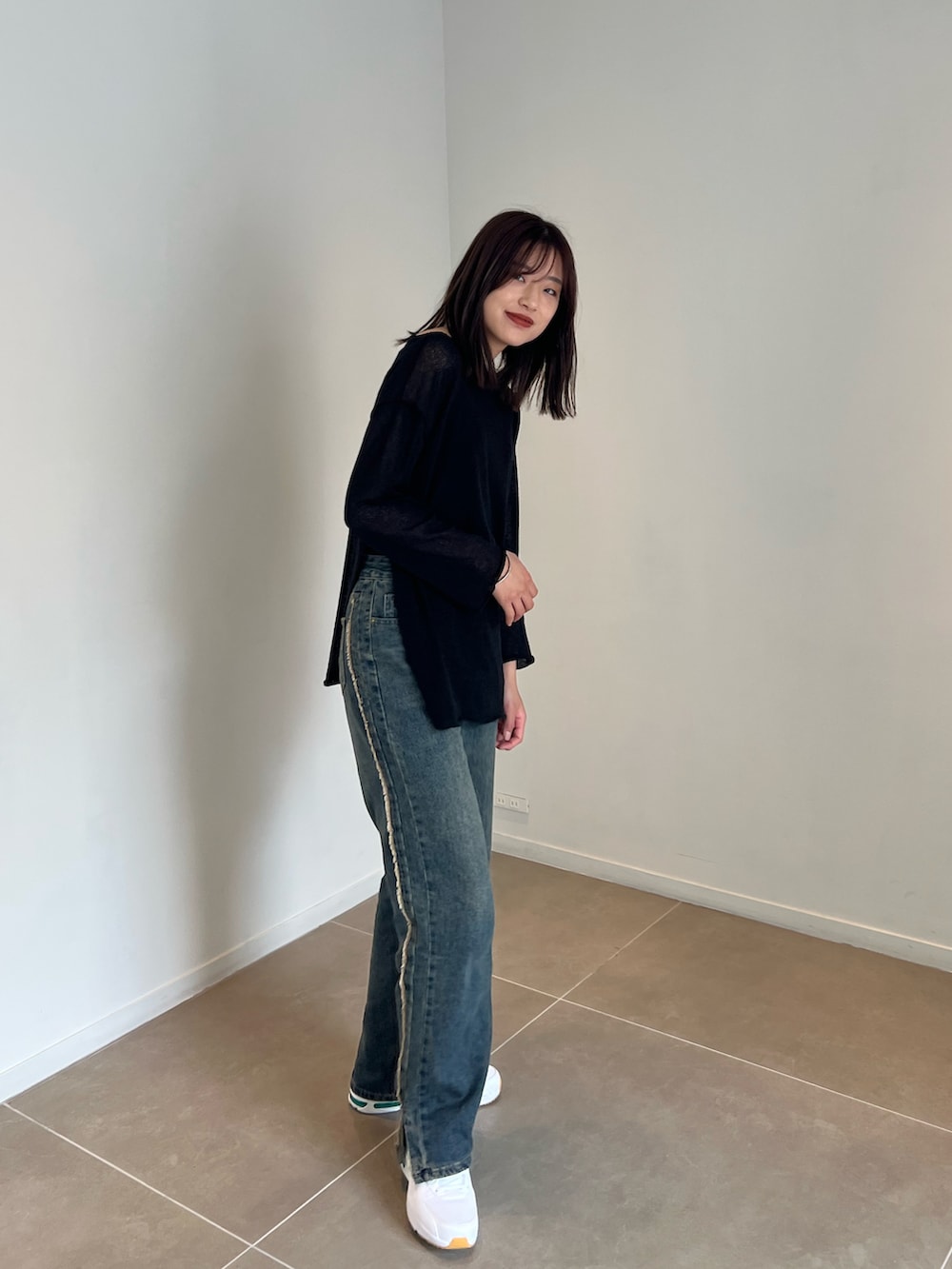 ブラック系のニット/セーター、ブルー系のデニムパンツを着用したレディースの夏コーディネートの2枚目の写真